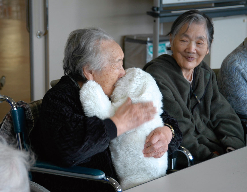 お年寄りの女性がパロを抱きしめている写真
