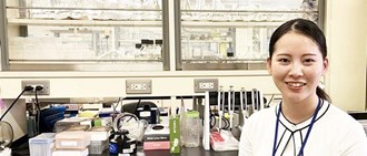 ナノバイオデバイス研究グループ 髙橋花奈子　研究員が実験室で微笑んでいる姿