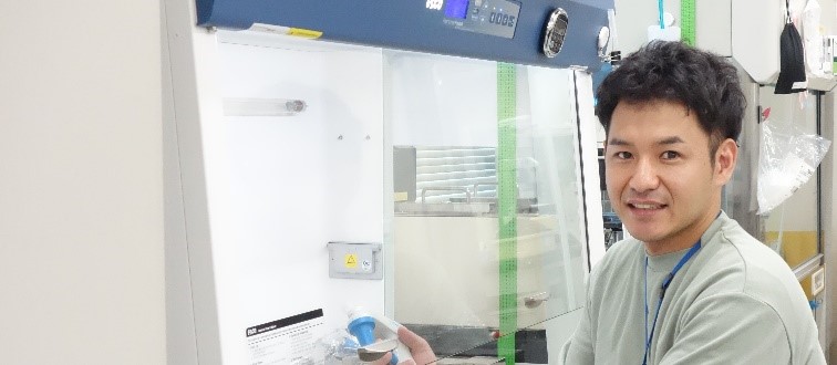 運動生理学・バイオメカニクス研究グループ 﨑谷直義　研究員が実験室で微笑んでいる姿