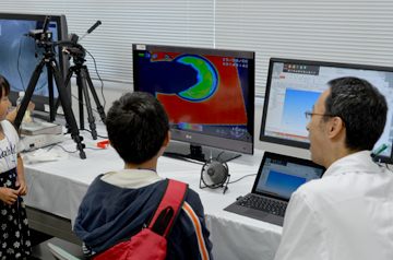 パソコン画面を見つめる子どもと説明する研究員