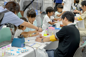 研究者に教わりながらスポイトを使う親子