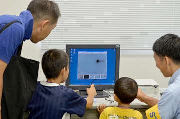 ハンディ顕微鏡の拡大映像をモニターで確認する様子