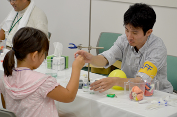 スポイトを使う子どもに、研究者が手を添えてサポートしている様子