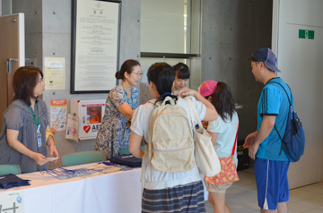 受付でスタッフが来場者に資料を渡している様子