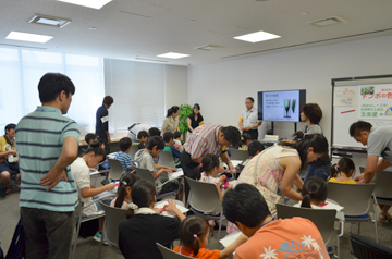 説明を聞きながら工作する子どもとそれを見守る大人たち