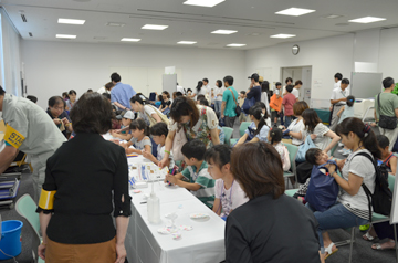 体験教室で多くの親子が席について作業している様子