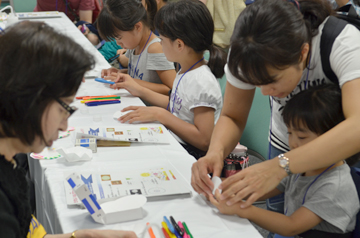 机で工作に取り組む子どもとそれを手伝う大人