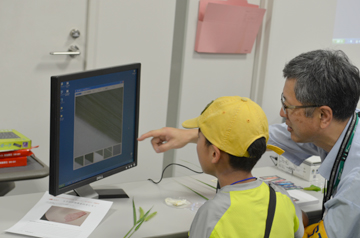 モニターの画像を示しながら子どもに説明する研究者