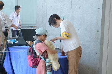 アザラシロボットのパロを持った子供と説明している女性