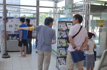 展示エリアの方向を指し示して来場者に案内するスタッフ