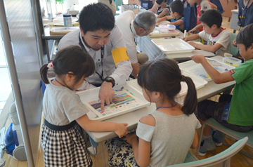 スタッフと向かい合って座り説明を聞く子供たち