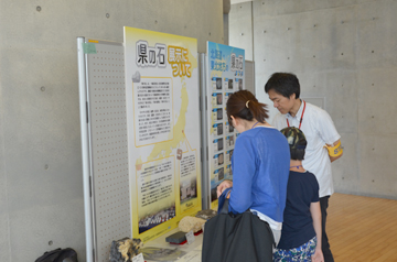 展示パネルを親子が読み、スタッフが説明している様子