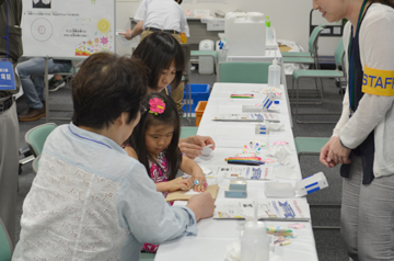 実験材料を前に、スタッフが子どもに手順を案内している様子