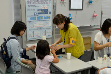 スタッフが子どもに工作体験をサポートしている様子