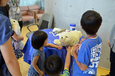 子どもたちが白いあざらしロボットパロを触っている様子