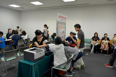 測定ブースで来場者がスタッフの案内を受けている様子