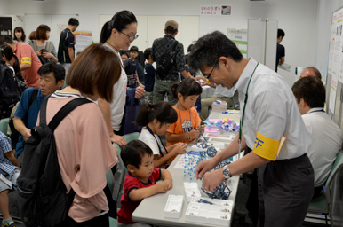 体験ブースでスタッフが子どもに作業を説明している様子