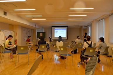 会場で参加者がスクリーンの講義を見ている様子