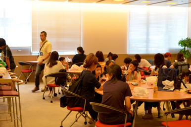 休憩スペースの丸テーブルで、来場者が飲食や談話をしながら過ごしている様子