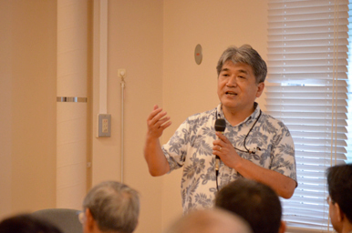 講演会の会場で、マイクを持った講師が話をしている様子