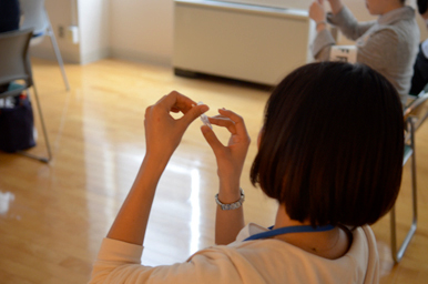 参加者が指先を使って小さな材料を組み立てる作業に取り組んでいる様子