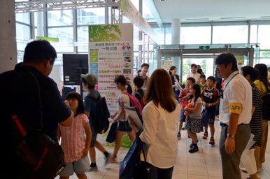 イベント会場の入口で、来場者がスタッフの案内を受けながら出入りしている様子