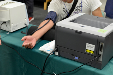 腕に血圧計のカフを巻き、測定装置に接続して血圧を測っている様子