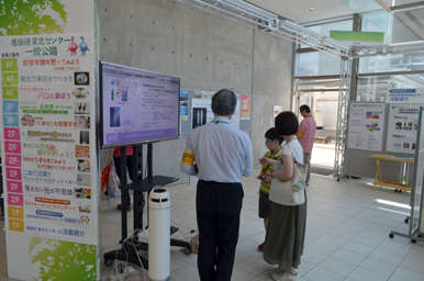 館内の案内表示の前で、モニターに映る展示内容を見ている来場者