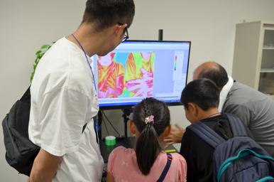 モニターに表示されたサーモグラフィーの画像を、スタッフと子どもたちが一緒に見ている様子