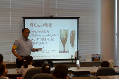 スクリーンを使って光の性質を説明する講師と、その話を聞く参加者たち
