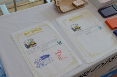 イラスト入りの勝利証明書とスタンプ台が机に並べられている様子