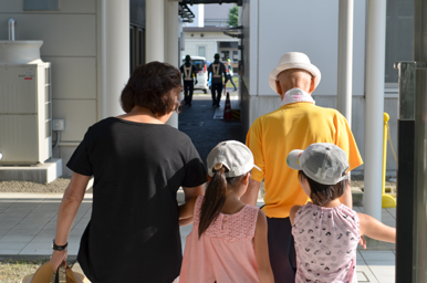 通路を歩く大人と子どもたちが並んで前に進んでいる様子