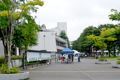 キャンパスの広場に設けられた案内テントと、その周辺を行き交う来場者の様子