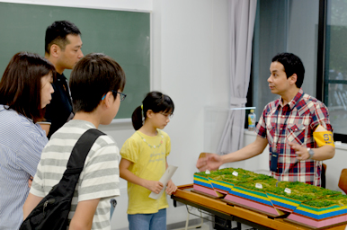 地層の模型を前に、スタッフが来場者に仕組みを解説している様子