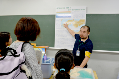 地図のパネルを指し示しながら来場者に説明するスタッフ