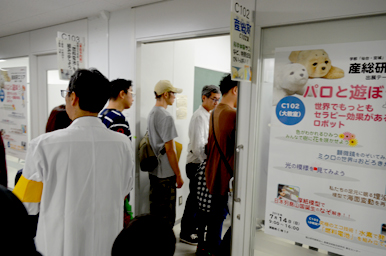 体験教室の入口前で案内ポスターを見ながら順番を待つ来場者たちの様子