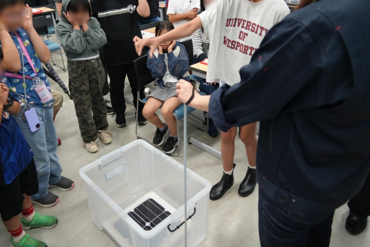 太陽電池モジュールに鉄の玉を落として、強度を確認する実験をしている様子