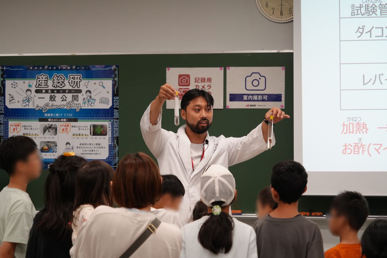 酵素実験で反応後の試験管を比較しながら説明する様子